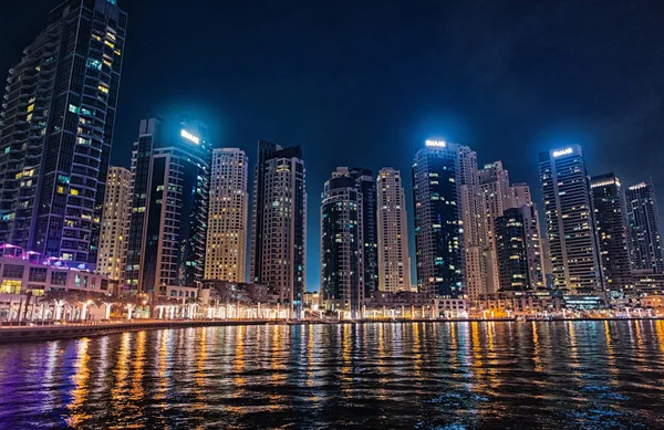 Dubai, Emiratos Árabes Unidos - 26 de diciembre de 2017: paisaje urbano del distrito de Dubai Marina por la noche. Edificios con reflejos luminosos en el agua. Arquitectura o estructura y diseño. Viajes y vacaciones — Foto de Stock