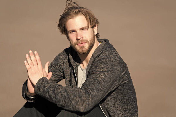 Bearded man with long blond hair outdoor. Macho with beard in casual sportswear on sunny day. Fashion guy with stylish haircut. Mens beauty at barber and hair salon. Lifestyle for young man