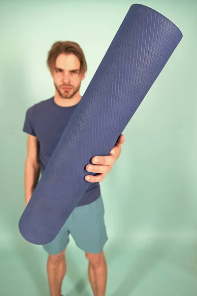 Yoga ou pilates tapis en main de l'homme flou. Tapis bleu roulé à la main. Équipement de gymnastique pour l'entraînement et l'entraînement. Yoga ou pilates et activité sportive — Photo