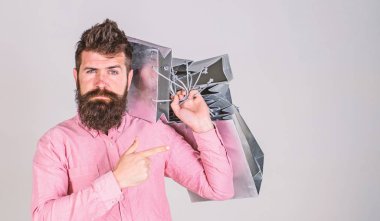 Öneri kavramı. Alışveriş satış sezonu üzerinde adam çanta işaret. Sakal ve bıyık taşır grup alışveriş torbaları, gri arka planı olan adam. Satın almak için ciddi bir yüz üzerinde hipster önerir