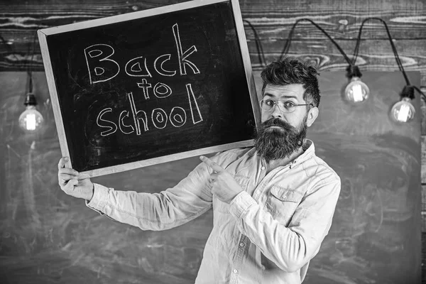 Lehrerin mit Brille hält Schultafel mit Titel zurück in die Schule. Gymnasialkonzept. Mann mit Bart und Schnurrbart im strengen Gesicht begrüßt Studenten, Kreidetafel im Hintergrund — Stockfoto