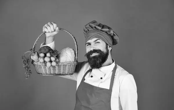 Людина з бородою на зеленому тлі. Шеф-кухар тримає овочі — стокове фото