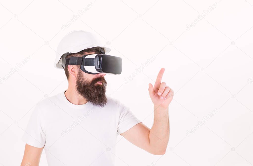 Man with beard in protective helmet using digital touch screen. Brutal bearded construction boss wearing VR headset isolated on white background. Bearded builder experiencing virtual reality