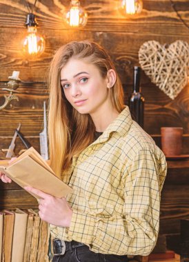 Kız sıcak atmosferde şiir okuma. Bayan kareli giysiler içinde rüya gibi yüz kitap, şiir okuma tutar. Ahşap vintage iç gündelik kıyafeti kız şiir tadını çıkarın. Şiir akşam kavramı