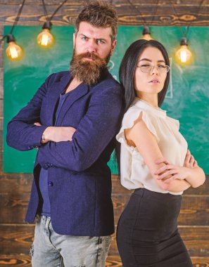 Adam sakallı ve öğretmen stand sırt sırta, kara tahta arka plan ile. Okul personeli kavramı. Öğretmen, öğretmen bak kendine güvenen. Akıllı bir adam ve yeşil arka plana karşı duran kadın portre