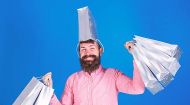 Modaya uygun sakal ve güler yüz üzerinde mavi arka plan izole olan adam. Hippi pembe gömlekli alışveriş, büyük spender yapıyor. Konsept alışveriş gümüş çanta taşıyan ve yorgunluk bir şapka, olarak mutlu sakallı adam