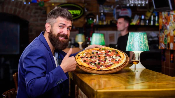 Hipster client sit at bar counter. Man received delicious pizza. Enjoy your meal. Cheat meal concept. Pizza favorite restaurant food. Fresh hot pizza for dinner. Hipster hungry eat italian pizza