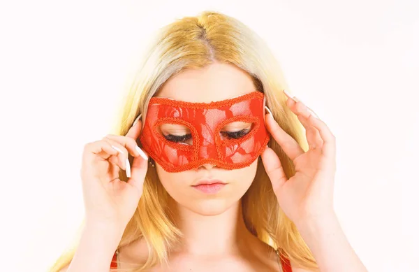 Woman on mysterious face play role game, visit masquerade. Girl with long blonde hair wears mask. Lady with long white manicure hold mask on face, white background, isolated. Mysterious woman concept.