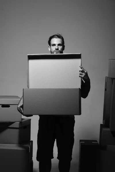 Guy holds boxes near chest, copy space. Man with beard