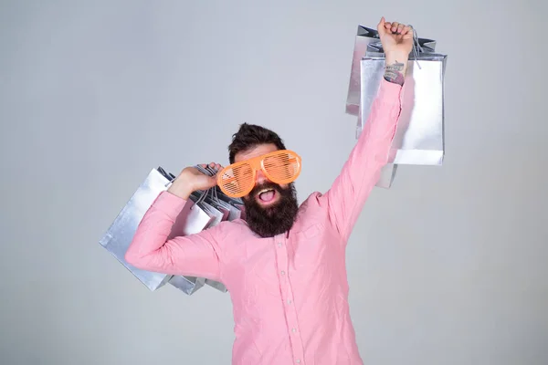 Compras el viernes negro. Feliz compra con bolsas de papel. Consumidor adicto a las compras. Cómo prepararse para sus próximas vacaciones. Hombre barbudo hipster usar gafas de sol mientras llevar mucho bolsas de compras —  Fotos de Stock