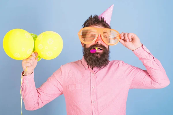 Unterhaltungskünstler leitet Wettbewerb bei Kinderparty, internationaler Kindertagsfeier. bärtiger Mann mit Geburtstagskappe, riesiger Brille, Partylaune und gelben Luftballons, die Spaß haben, Glückskonzept — Stockfoto