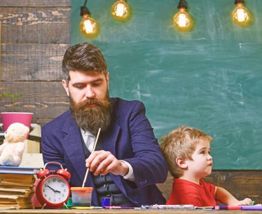 Öğretmen sakallı, çizim arka plan kara tahta sınıf, küçük oğlu yakınındaki, takılmak iken Peder. Sanat ders kavramı. Çocuk ve resim öğretmeni meşgul yüz boyama,