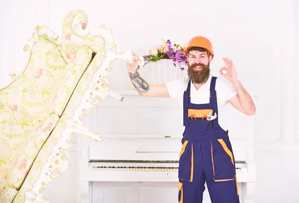 Feliz constructor reubicando sofá vintage antes de redecorar. Movimiento sonriente con barba elegante y bigote que muestra un gesto aceptable en la habitación blanca — Foto de Stock