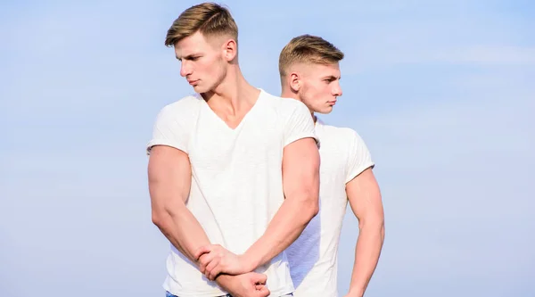 Handsome strong twins. Men strong muscular athlete bodybuilder posing confidently in white shirts. Sport lifestyle and healthy body. Attractive twins. Men twins muscular brothers sky background