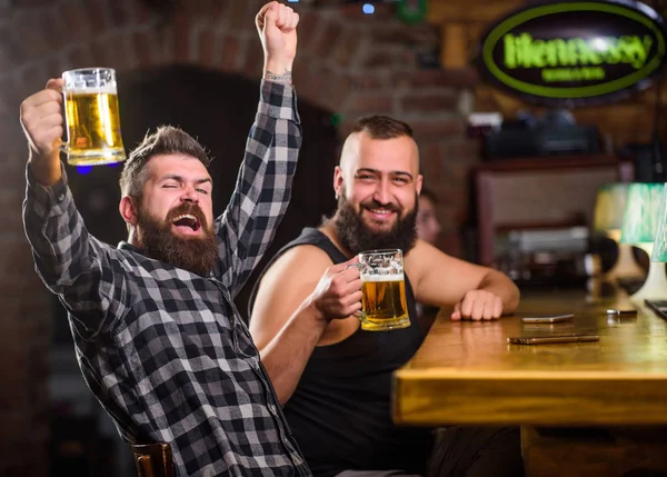 Refreshing beer concept. Hipster brutal man drinking beer with friend at bar counter. Men drunk relaxing having fun. Alcohol drinks. Friends relaxing in pub with beer. Men drinking beer together