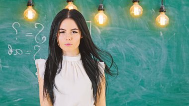 Bayan öğretmen sakin yüzünde kara tahta önünde duruyor. Beyaz bluz uzun saçlı kadın sınıfta durumda. Akıllı seksi kadının yanına hesaplamalar, kopya alanı ile yazı tahtası. Elit okul kavramı