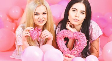 Kızlar balonlar yatıyordu, kalp oyuncaklar, pembe arka plan almıştır. Kız kardeşim, arkadaşlarım pijama pijama partisinde. Sevgililer günü kavramı. Sarışın ve esmer gülümseyen yüzler aşk ve Tarih hakkında rüya üzerinde