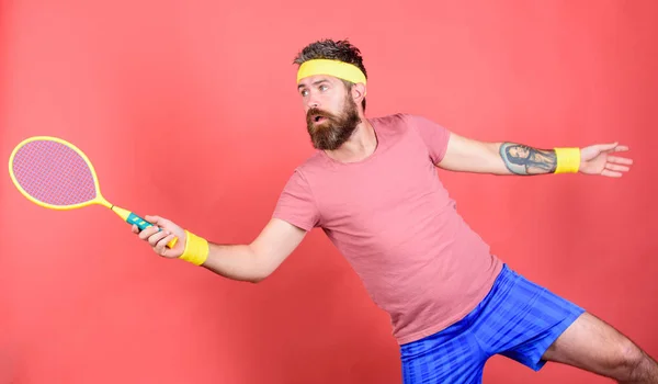 Man bearded hipster wear sport outfit. Tennis player beginner retro fashion. Concentrated on tennis court. Tennis sport and entertainment. Athlete hipster hold tennis racket in hand red background