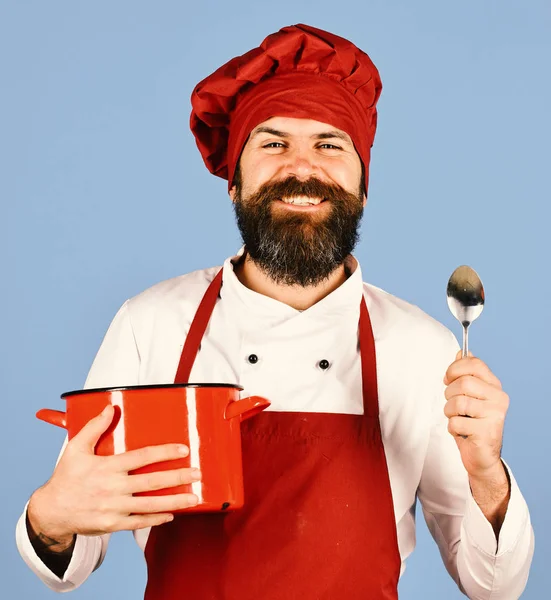 Man met baard houdt keukengerei op blauwe achtergrond. — Stockfoto