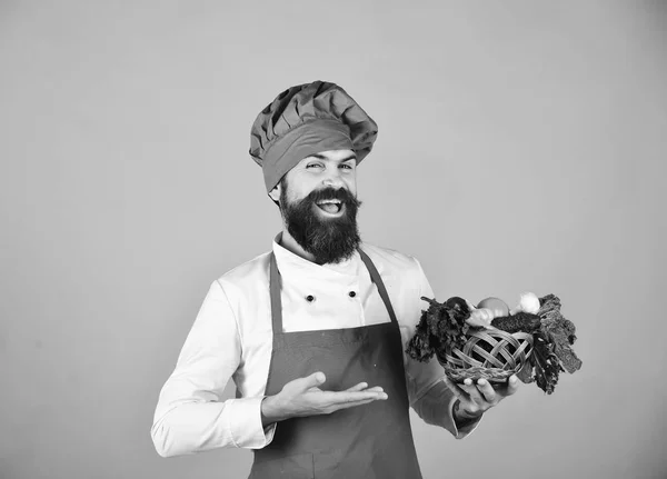 Cocinar con la cara alegre en uniforme de color burdeos presenta verduras —  Fotos de Stock