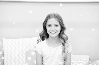 Çocuk mükemmel kıvırcık saç modeli şirin görünüyor. O kremi veya maske ile organik yağlar saç parlak ve sağlıklı tutmak için kullanır. Güzellik Salonu ipuçları. Uzun kıvırcık saçları gri iç arka plan ile kız çocuk