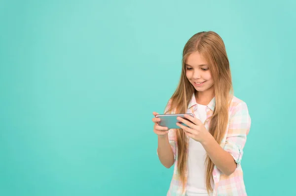 Pretty blogger. Small girl child with smartphone. Small girl using mobile phone. Adorable child learning new technology. Cute mobile phone technology user. Watching video on mobile device, copy space