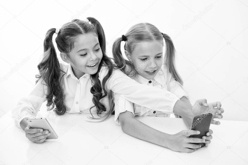 school break for happy little girls using smartphones. little girls using smartphones on school break having fun.