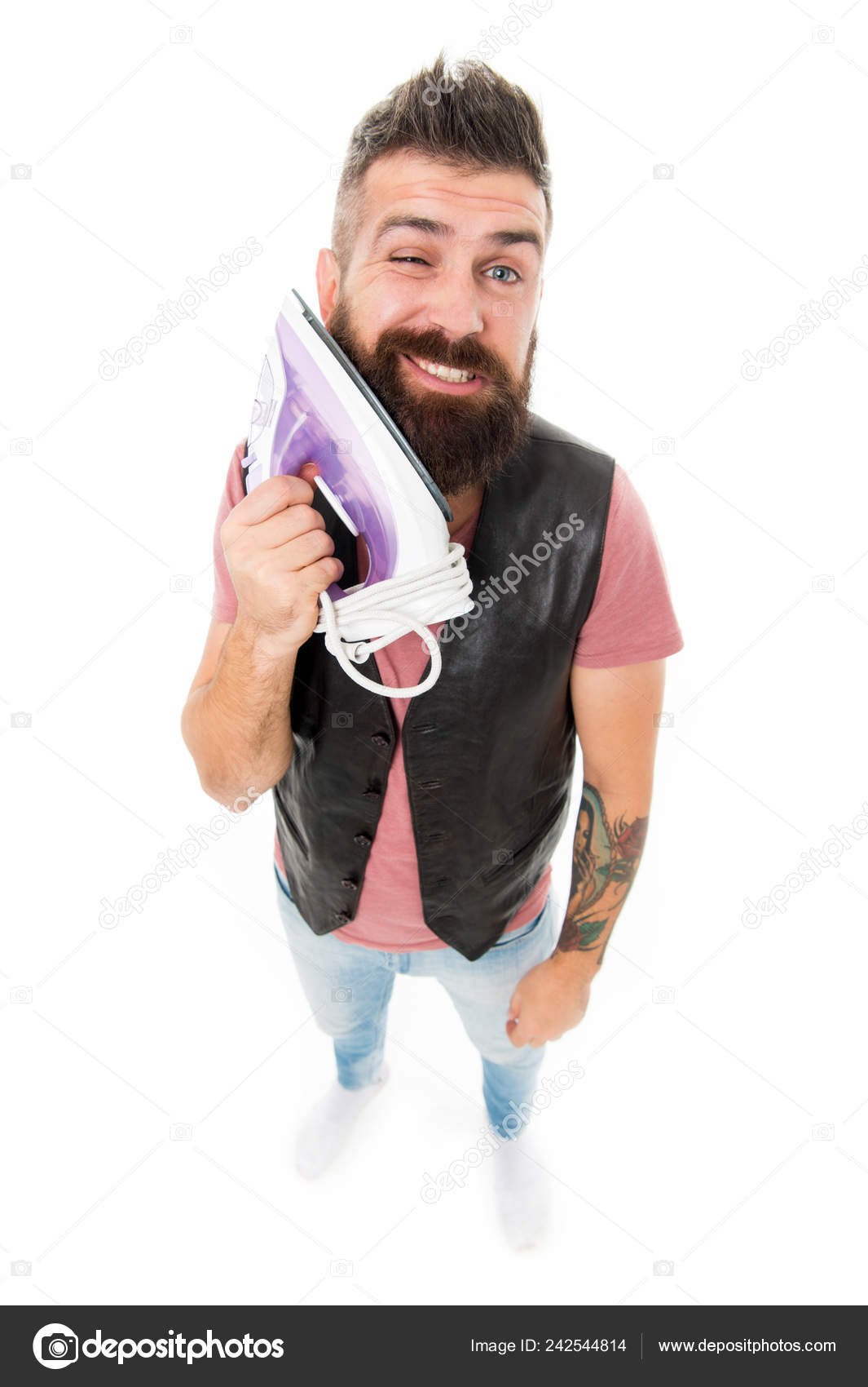 Styling his beard. Hipster smoothing his beard hair with electric ironing  tool. Bearded man with clothes iron. Unshaven brutal man with iron in hand.  Household ironing. Providing household services Stock Photo by ©