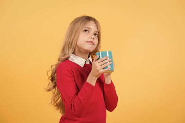 Düşünme yüz çocukla tutun turuncu zemin üzerine mavi Kupası