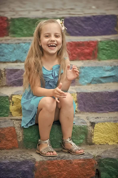 Petite fille heureuse en robe bleue sur des escaliers colorés — Photo