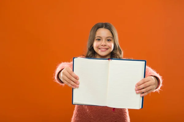 看看这个。女孩拿着书橙色的背景。儿童显示打开的书籍或记事本页。书店概念。可免费阅读书籍。童年文学。发展和教育 — 图库照片