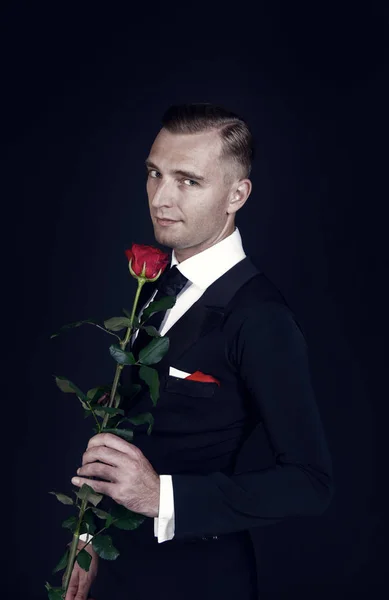 Homme à la rose rouge sur fond sombre — Photo