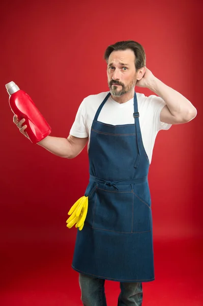 Bărbat în șorț cu mănuși ține sticla de plastic lichid săpun agent chimic de curățare. Astăzi e ziua curăţeniei. Bărbat care face curăţenie acasă. Cu paza curăţeniei şi ordinii. Servicii de curățenie și datoria gospodăriei — Fotografie, imagine de stoc
