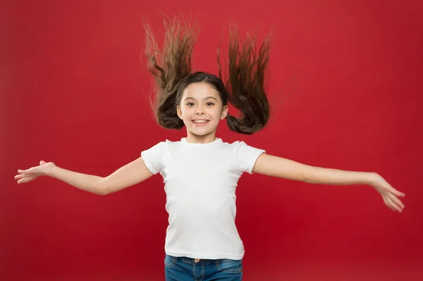 Enfant sourire visage mignon vivre une vie heureuse insouciante. Profitez de chaque instant. Jeune et libre. Joyeux enfant fille aux cheveux longs sur fond rouge. Bonheur et joie. Des émotions positives. Garde et éducation des enfants — Photo