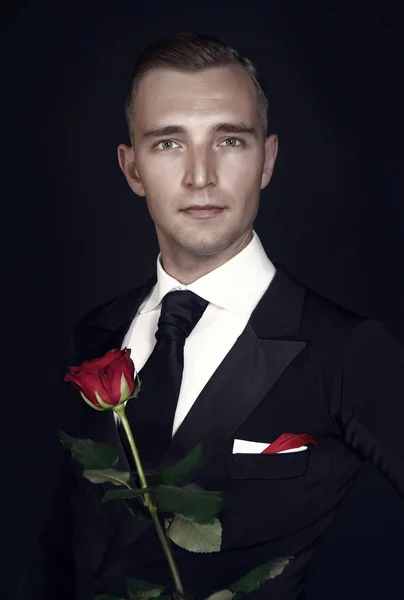 Frumos om de afaceri ține floarea peste fundal gri — Fotografie, imagine de stoc
