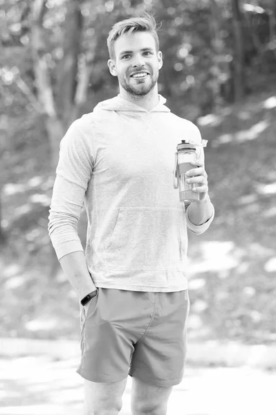 Homem atleta segurar garrafa cuidados hidratação corpo após o treino. Bebida de vitamina refrescante após grande treino. Homem aparência atlética detém garrafa de água. Atleta beber água após o treinamento no parque — Fotografia de Stock