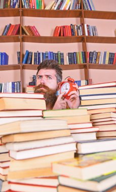 Öğretmen ya da sakal Kitaplığı'nda eğitim ile öğrenci. Adam, çalar saat ile kitap yığınları dışarı bakmak bilim adamı. Düşünceli yüz dinleme erkek saat, raflardan arka plan üzerinde. Zaman stop kavramı