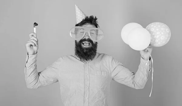 Mann mit Bart und Schnurrbart auf glücklichem Gesicht hält Luftballons, hellblauer Hintergrund. Hipster mit Riesenbrille feiern Geburtstag. Mann im Partyhut mit Feiertagsattributen feiert. Parteikonzept — Stockfoto