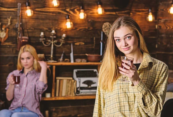 Amigos en caras relajadas en ropa a cuadros relajante, desenfocado. Chicas relajantes y beber vino caliente con especias. Descanse y relájese concepto. Amigos disfrutan del vino caliente en un ambiente cálido, interior de madera —  Fotos de Stock