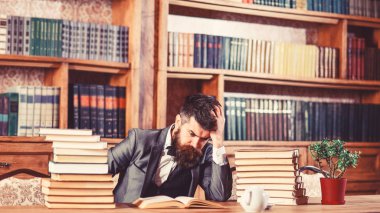 Zor konu, kafa karıştırıcı soru, çalışma, eğitim, zor iş, entelektüel araştırma kavramı. Adam ile pek çok kitap masada oturur. Olgun adam ciddi bir yüz ve düşünüyor. Adam kitaplığında okur