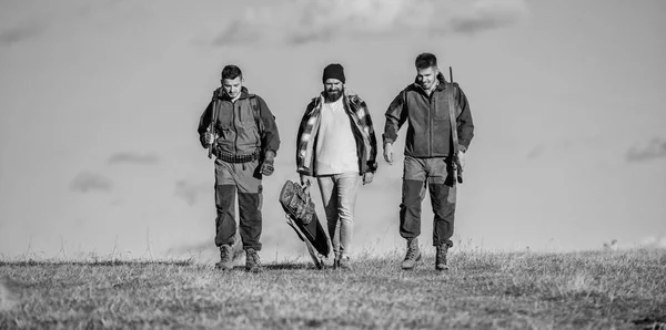 Caçadores com armas andam dia ensolarado de outono. Um passatempo brutal. Grupo homens caçadores ou gamekeepers natureza fundo azul céu. Tipos reunidos para caçar. Os homens carregam espingardas de caça. Caça como hobby e lazer — Fotografia de Stock