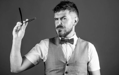 Erkek yelek papyon ile usturanın mavi arka plan tutun. Vintage sanat kavramı berber. Kuaför keskin ustura ile tıraşsız hippi. Berber Kuaför Salonu. İpuçları bakım Kuaför sakal