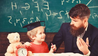Baba oğul matematik öğretiyor. Aritmetik ders kavramı. Öğretmen formal giyim ve öğrenci sınıfta kolej, kara tahta arka plan. Neşeli çocuk öğretmen ile eğitim