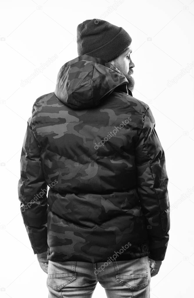 Man stand warm camouflage pattern jacket parka with hood isolated on white background. Hipster winter fashion. Guy wear hat and black winter jacket. Comfortable winter outfit. Winter stylish menswear