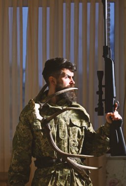 Hakem kavramı. Sakallı kamuflaj elbiseler giyer, arka plan perdeler. Avcı, silah ve geyik boynuzları ile acımasız hippi. Maço gamekeepers evinde avlamaya hazır sıkı yüzünde