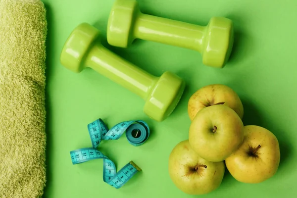 Dumbbells in bright color, measure tape, towel and fruit