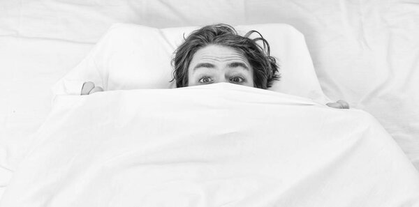 Bare feet of a man peeking out from under the cove. Lazy man happy waking up in the bed rising hands in the morning with fresh feeling relaxed. Happy guy in bed.