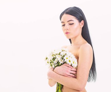 Bayan göğüsler üzerinde beyaz izole çiçekli kapsar. Kadın göğüslerini buket kapaklarla gizleme. Kanser meme kavramının. Sakin yüz çıplak kız papatya çiçeği göğüs önünde tutar.