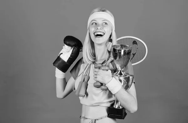 Mädchen erfolgreiche moderne Frau halten goldenen Pokal des Sportmeisters und Ausrüstung blauen Hintergrund. wie man Zeit für alles findet. Sportartikelgeschäft. Sport für jeden Tag. Sportgeschäft-Sortiment — Stockfoto