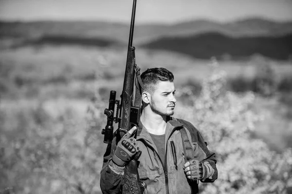 Guy bearded hunter spend leisure hunting on birds. Hunting masculine hobby concept. Man brutal guy gamekeeper nature background. Regulation of hunting. Hunter rifle gun stand top of mountain — Stock Photo, Image